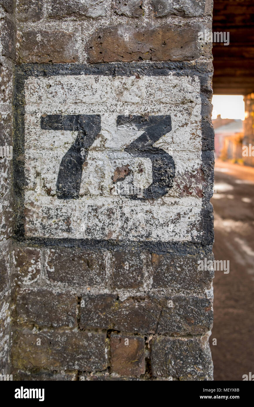 Dipinto il numero 73 sul vecchio muro in mattoni. Foto Stock