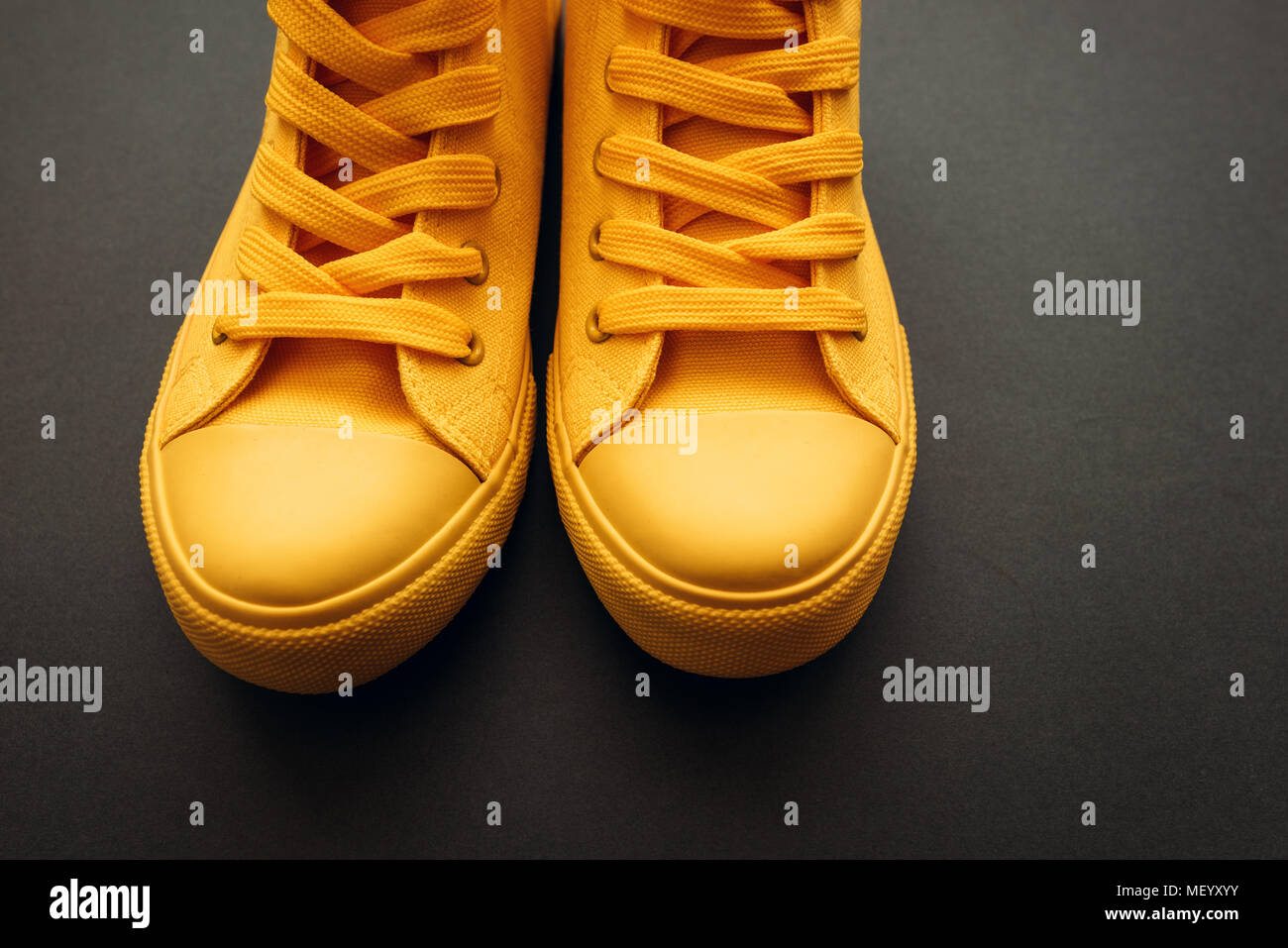 Elegante sneakers giallo su sfondo grigio con spazio di copia Foto Stock