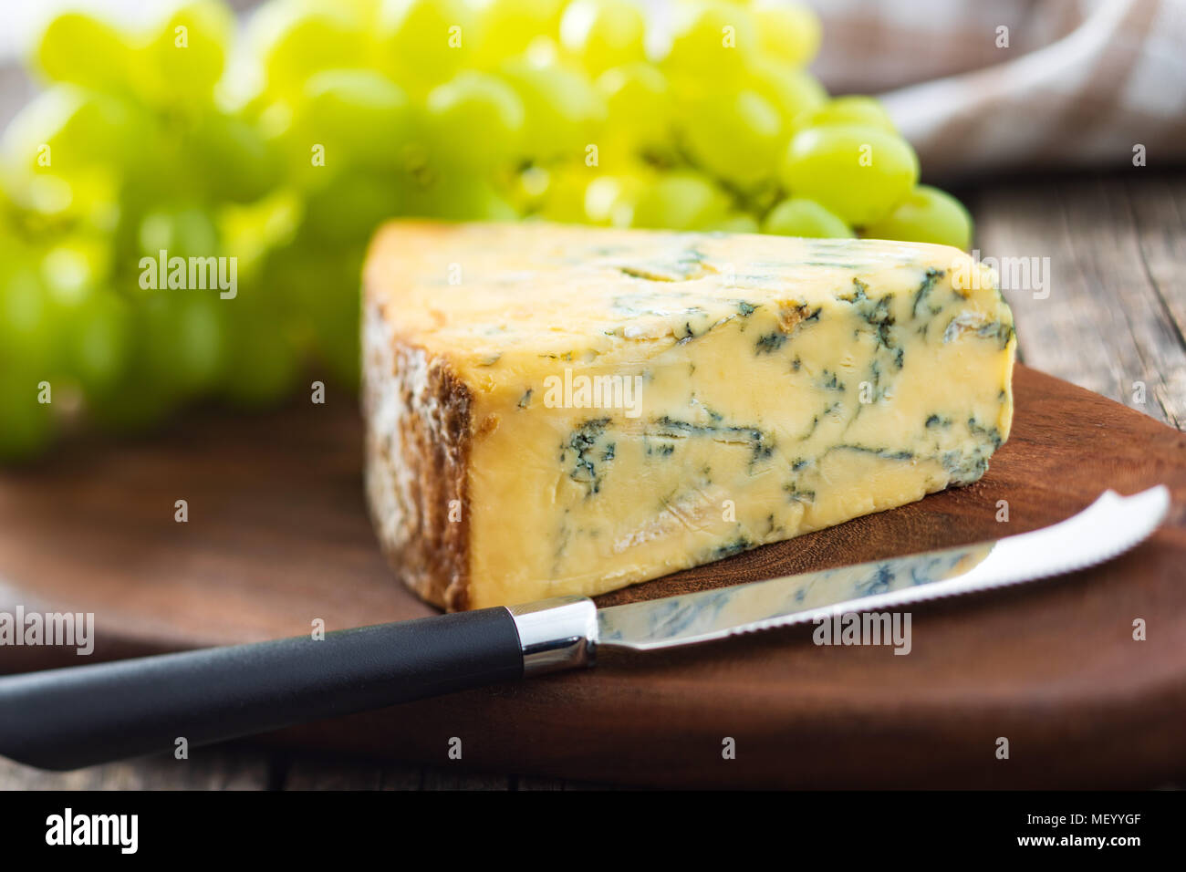 Gustoso formaggio blu con uve sul bordo di taglio. Foto Stock