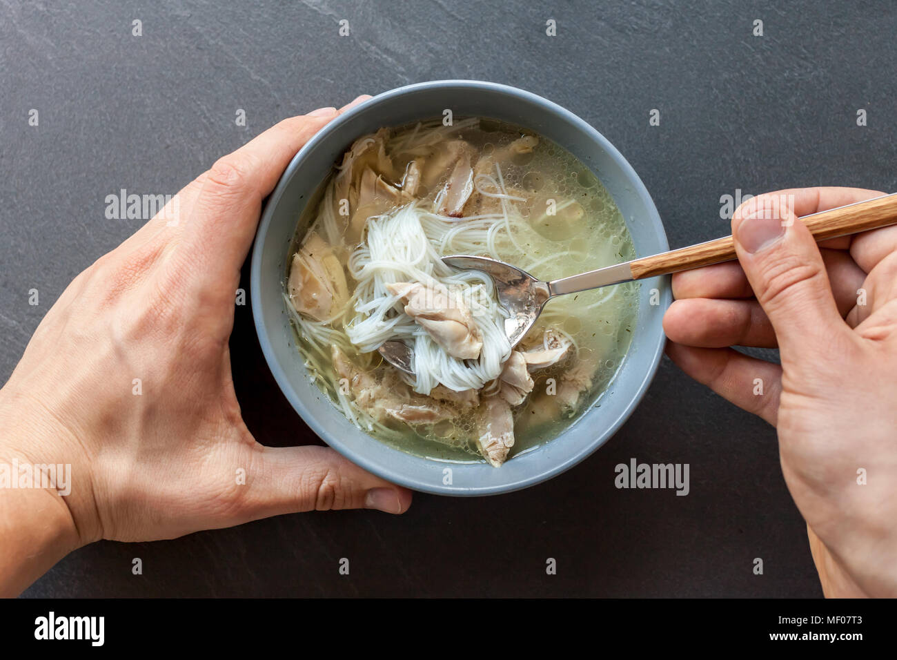 Zuppa asiatica di anatra con mani di uomo nero su sfondo di pietra Foto Stock