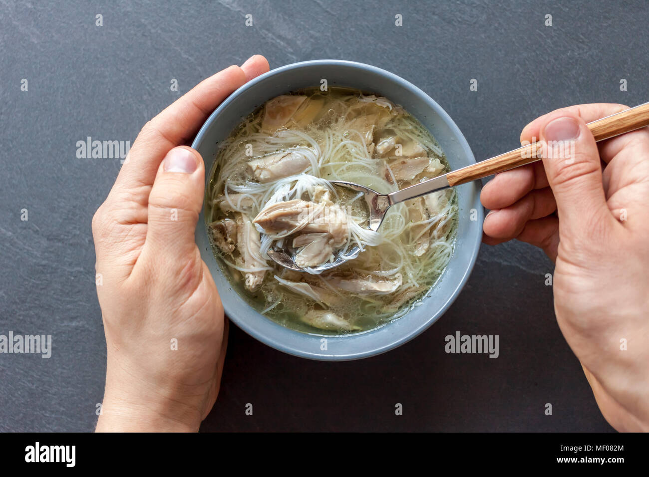 Zuppa asiatica di anatra con mani di uomo nero su sfondo di pietra Foto Stock