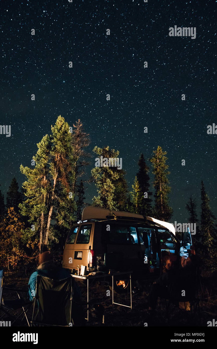 Canada, British Columbia, due uomini seduti sotto il cielo stellato in minivan di notte Foto Stock