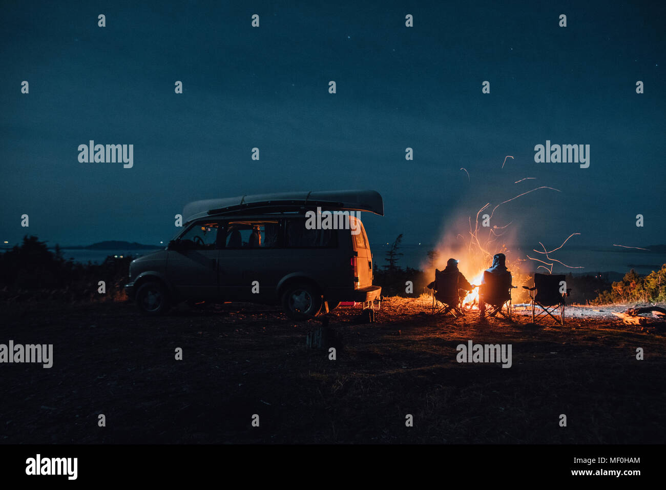 Canada, British Columbia, Prince Rupert, due uomini seduti al fuoco di campo in minivan di notte Foto Stock