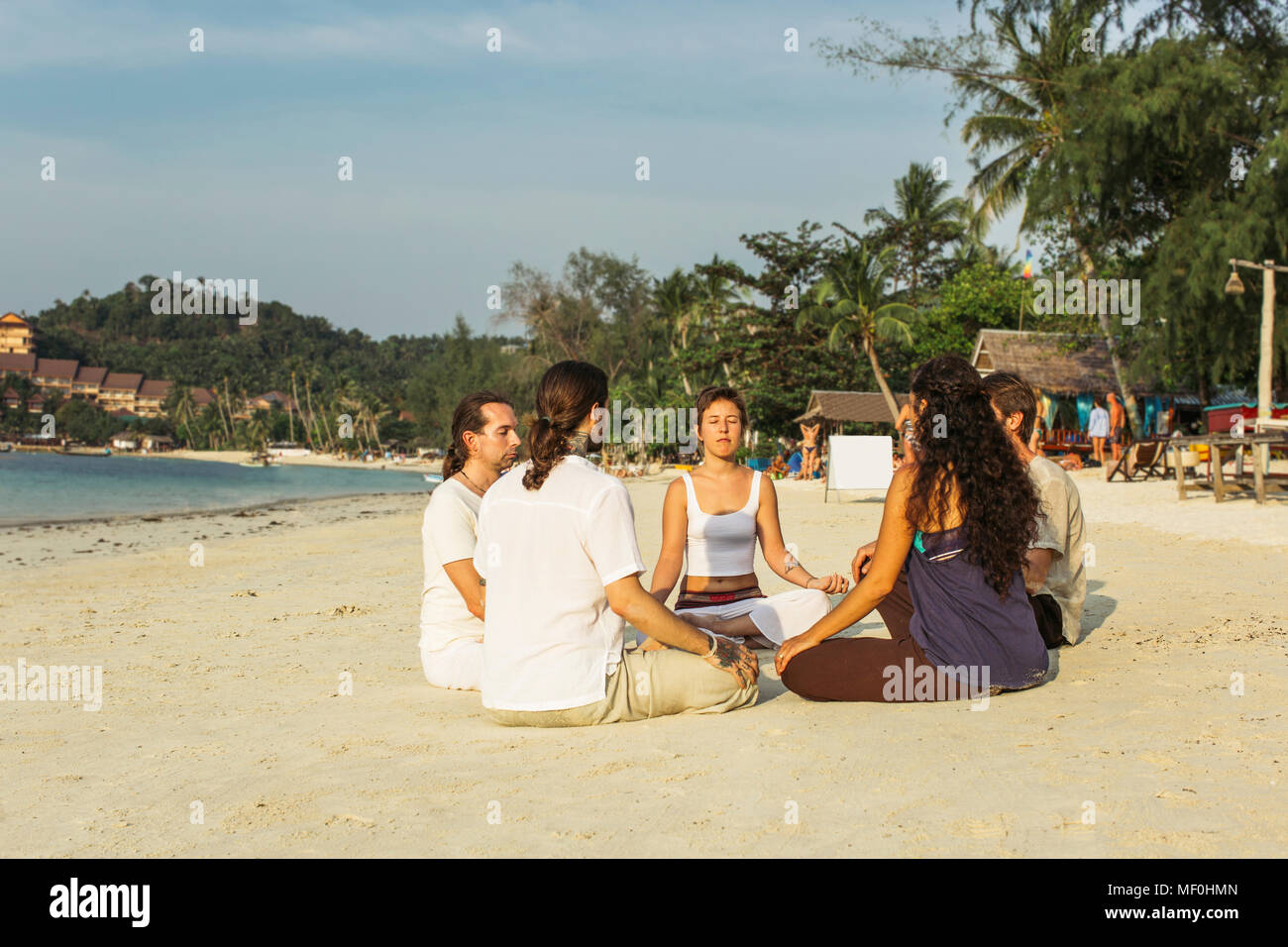 Thailandia Koh Phangan, gruppo di persone meditando insieme su una spiaggia Foto Stock