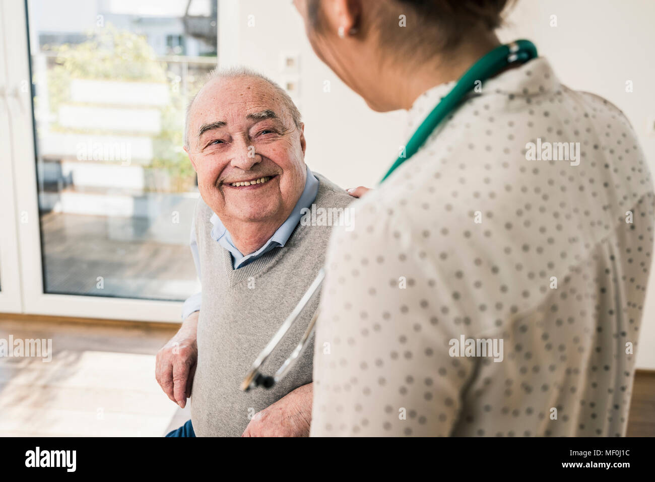 Senior uomo sorridente in un infermiere a casa Foto Stock