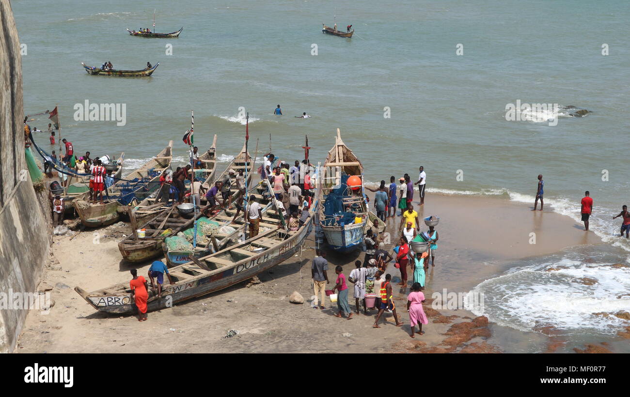 Barche da pesca e la gente sulla spiaggia vicino al fort di Cape Coast, in Ghana Foto Stock