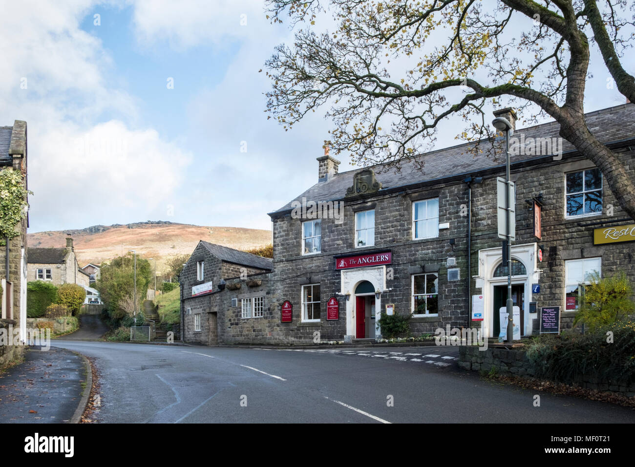 The Anglers pub nel villaggio di Bamford con Bamford bordo nella distanza che si eleva al di sopra del villaggio, Derbyshire, Peak District, England, Regno Unito Foto Stock
