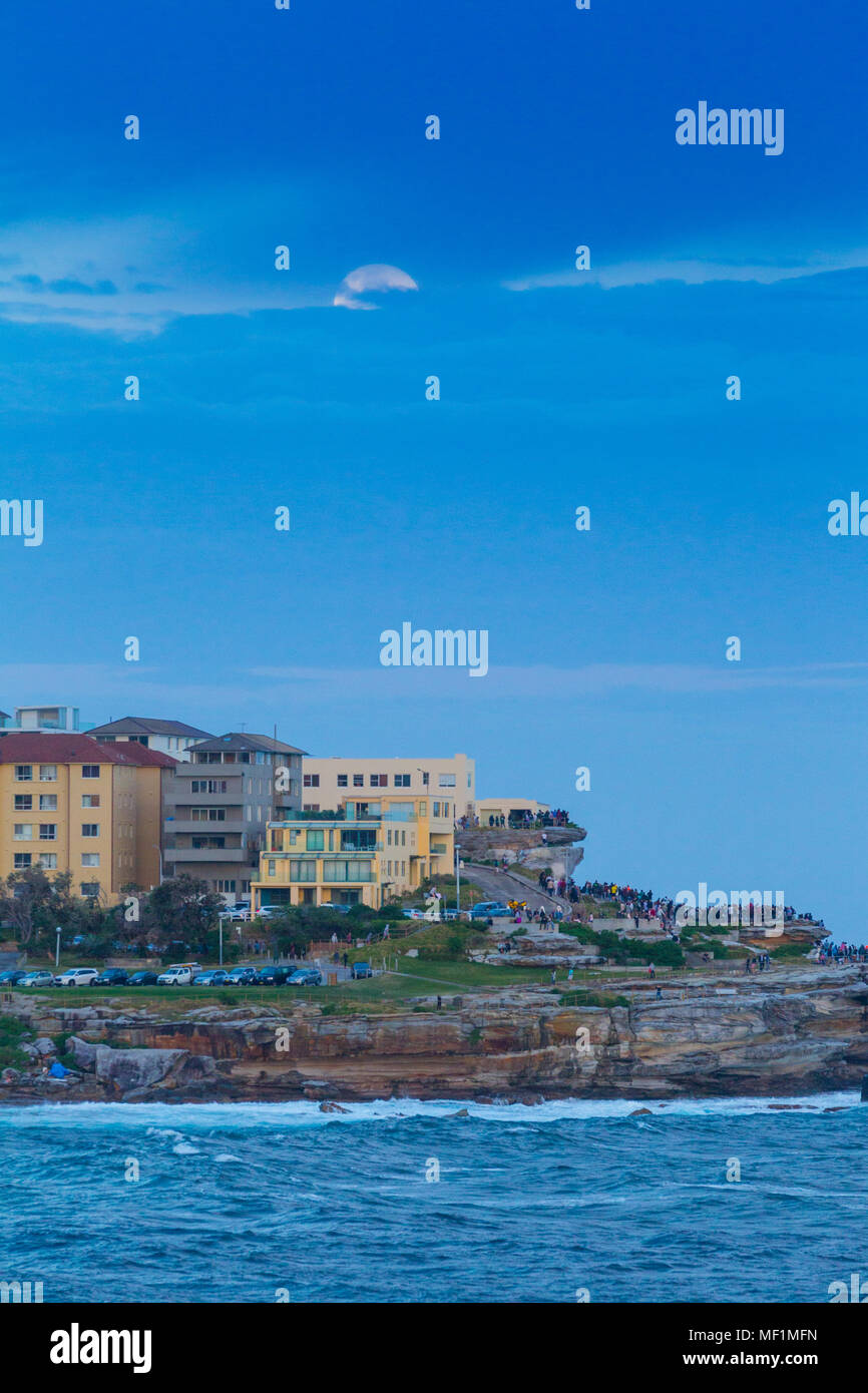 E grandi folle si radunarono sulla spiaggia Bondi promontori a testimoniare il 'super luna", la più grande luna piena visto per 70 anni. Una luna piena non sarà questa grande nuovamente fino a quando l'anno 2034. Nonostante la grande folla la luna di visibilità è stata oscurata dal livello basso nubi all'orizzonte. Foto Stock