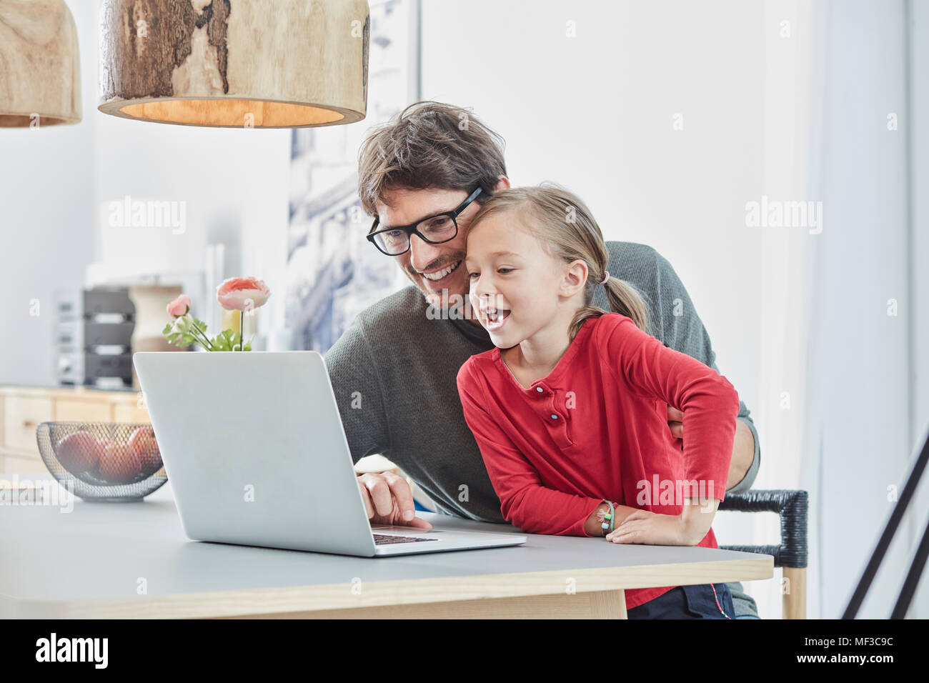 Felice padre e figlia utilizzando computer portatile sul tavolo a casa Foto Stock