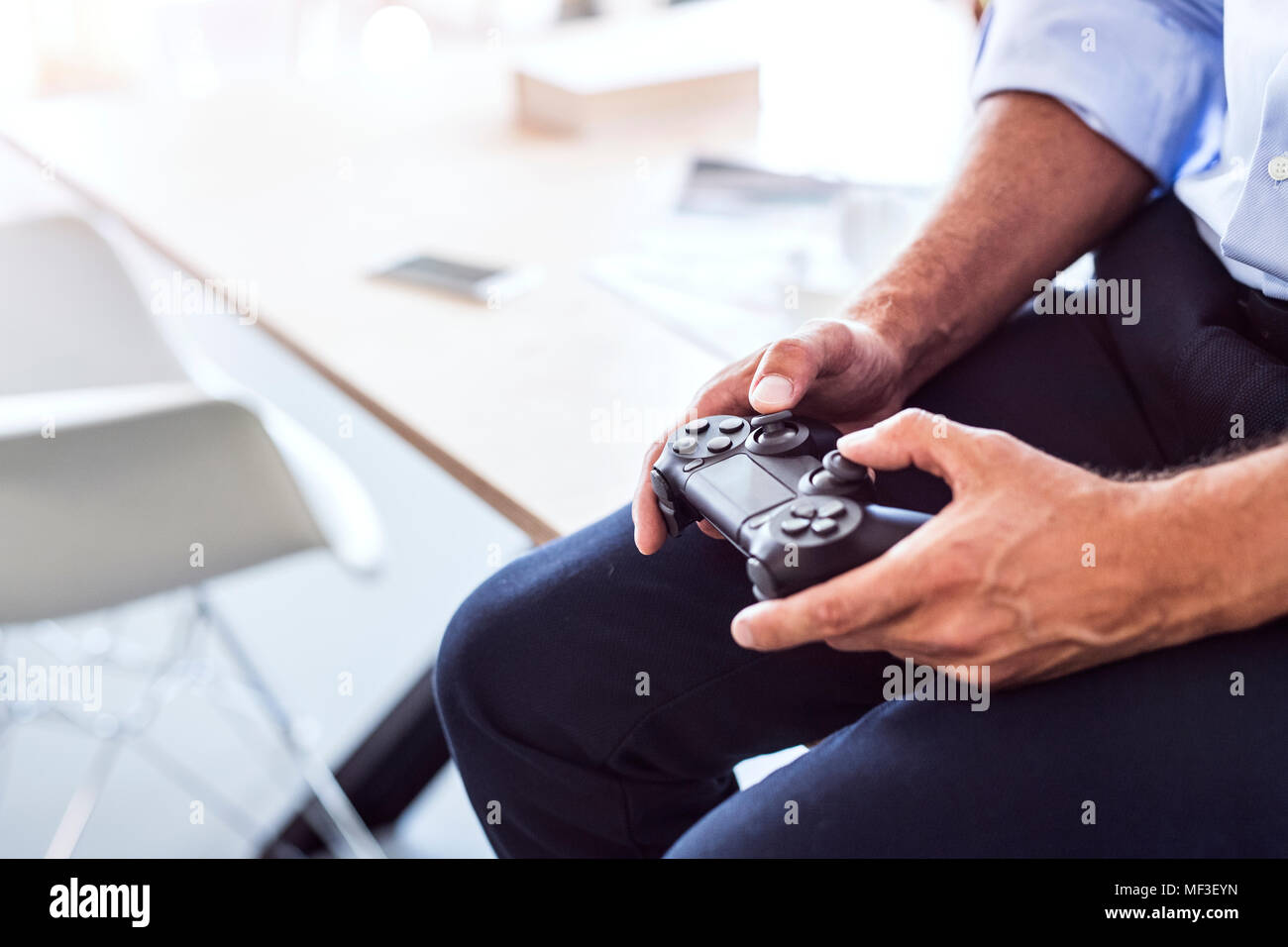 Close-up di imprenditore seduto sulla scrivania in ufficio tramite controller Foto Stock