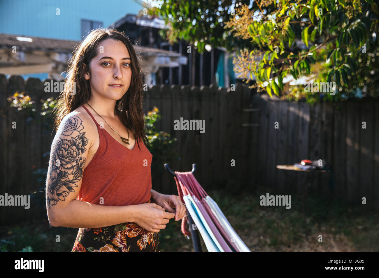 Ritratto di giovane donna con il tatuaggio in cortile Foto Stock