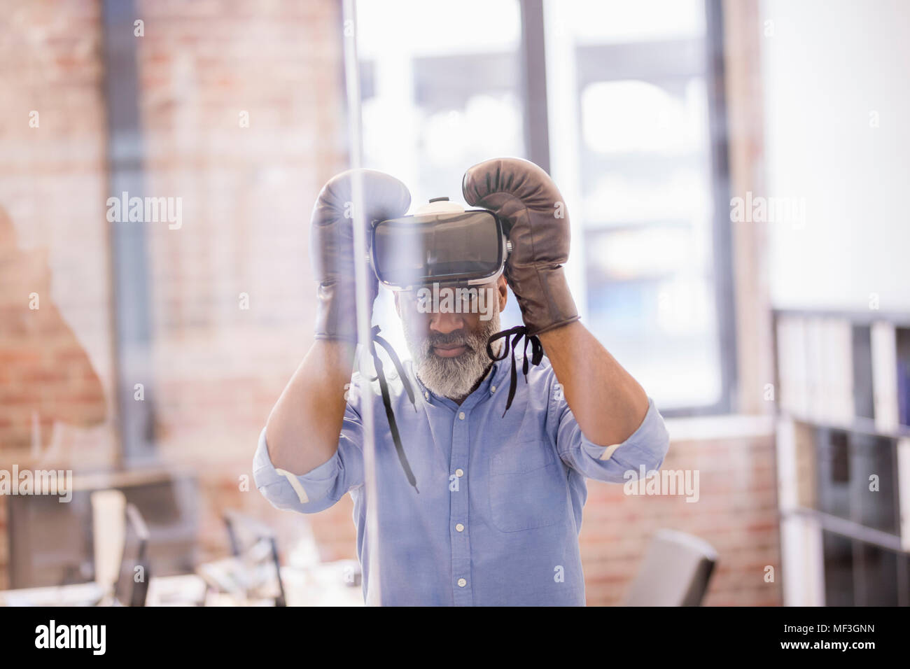 Ritratto di imprenditore con la realtà virtuale di occhiali e guanti da boxe in ufficio Foto Stock