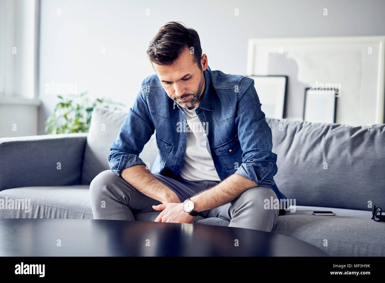 Preoccupato triste uomo seduto sul divano Foto Stock