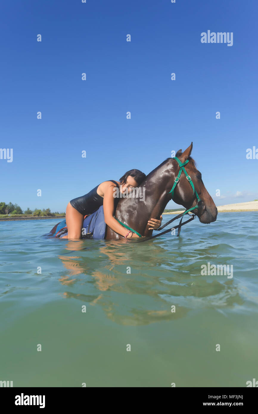 Indonesia, Bali, donna sdraiata sul cavallo, in acqua Foto Stock