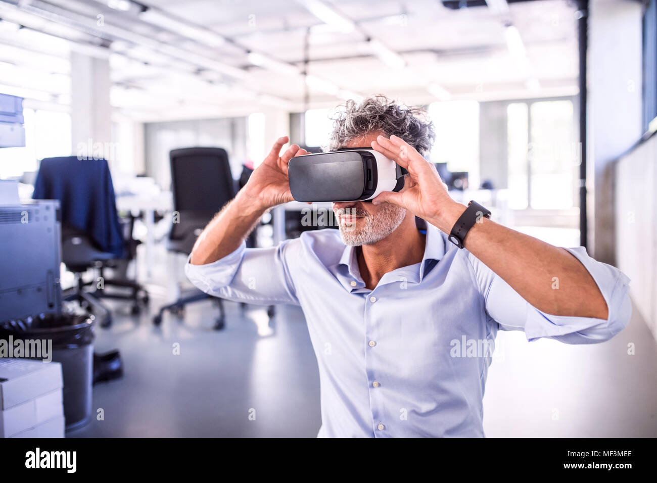 Imprenditore maturo indossando occhiali VR in office Foto Stock