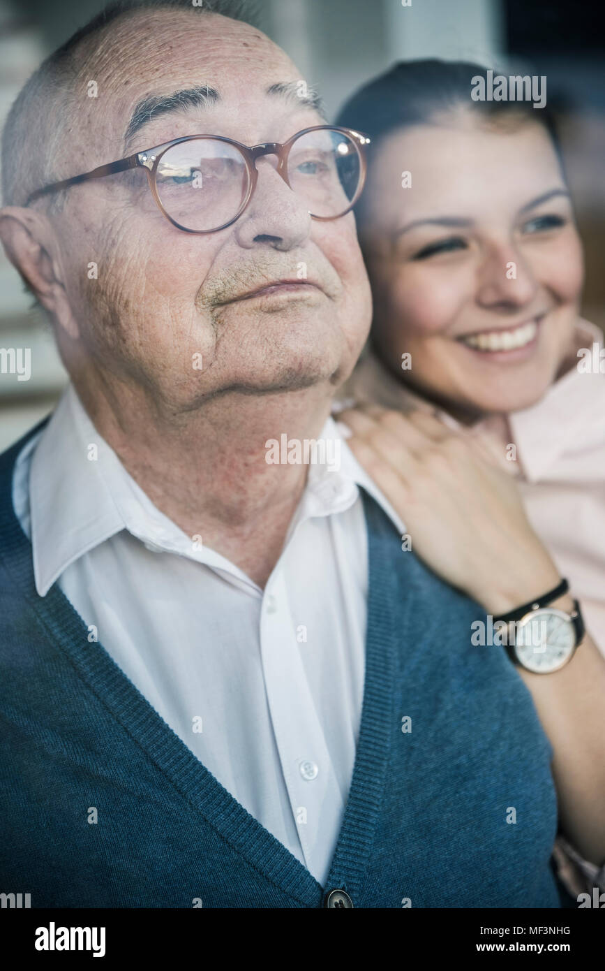 Ritratto di sorridente giovane donna con uomo senior presso la finestra Foto Stock