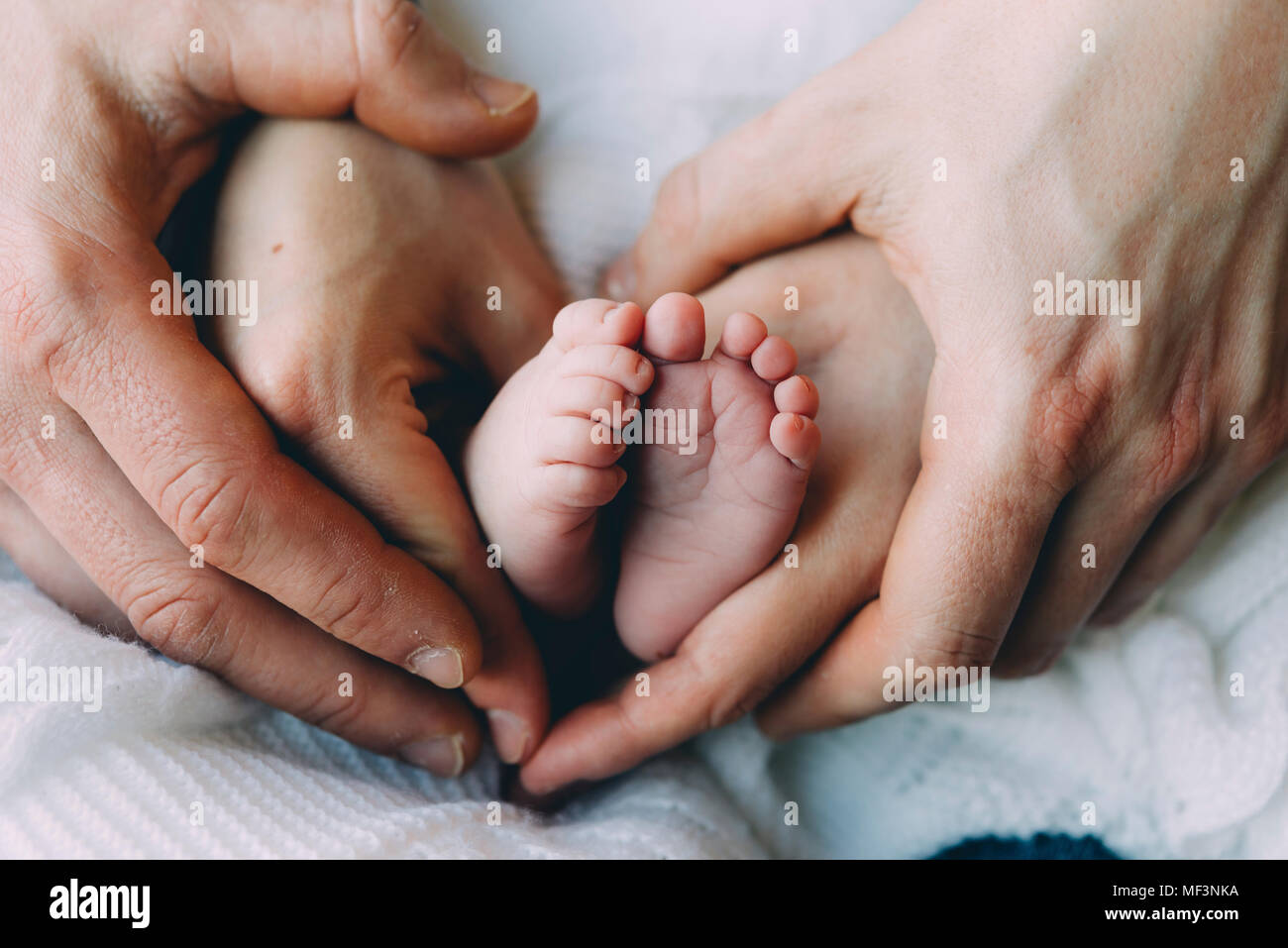 Di padre e di madre tenendo le mani del bambino in piedi Foto Stock