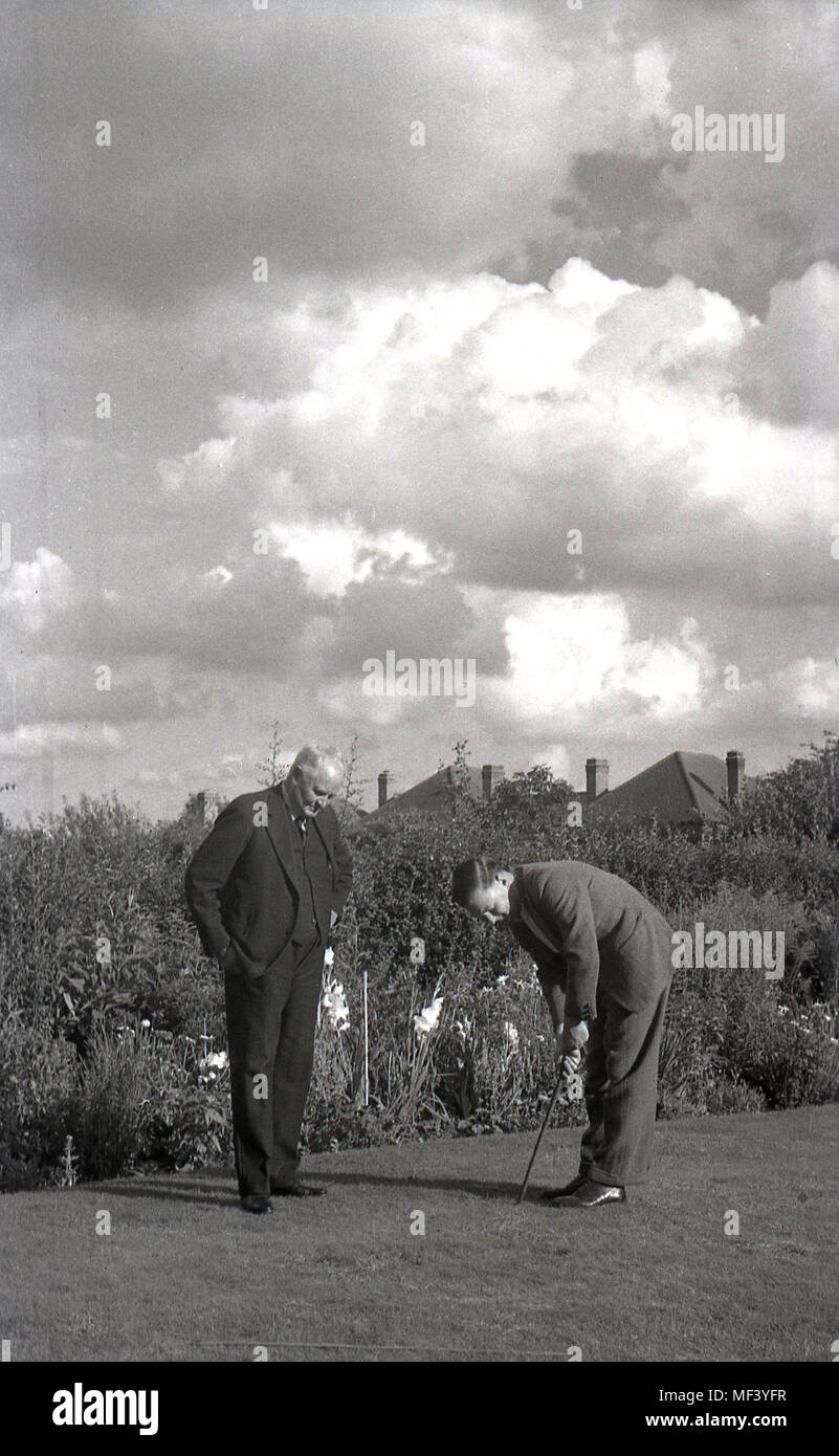 1950, storico, Londra, padre e figlio e nonno insieme sul prato del backgarden, avente una messa la concorrenza. Foto Stock