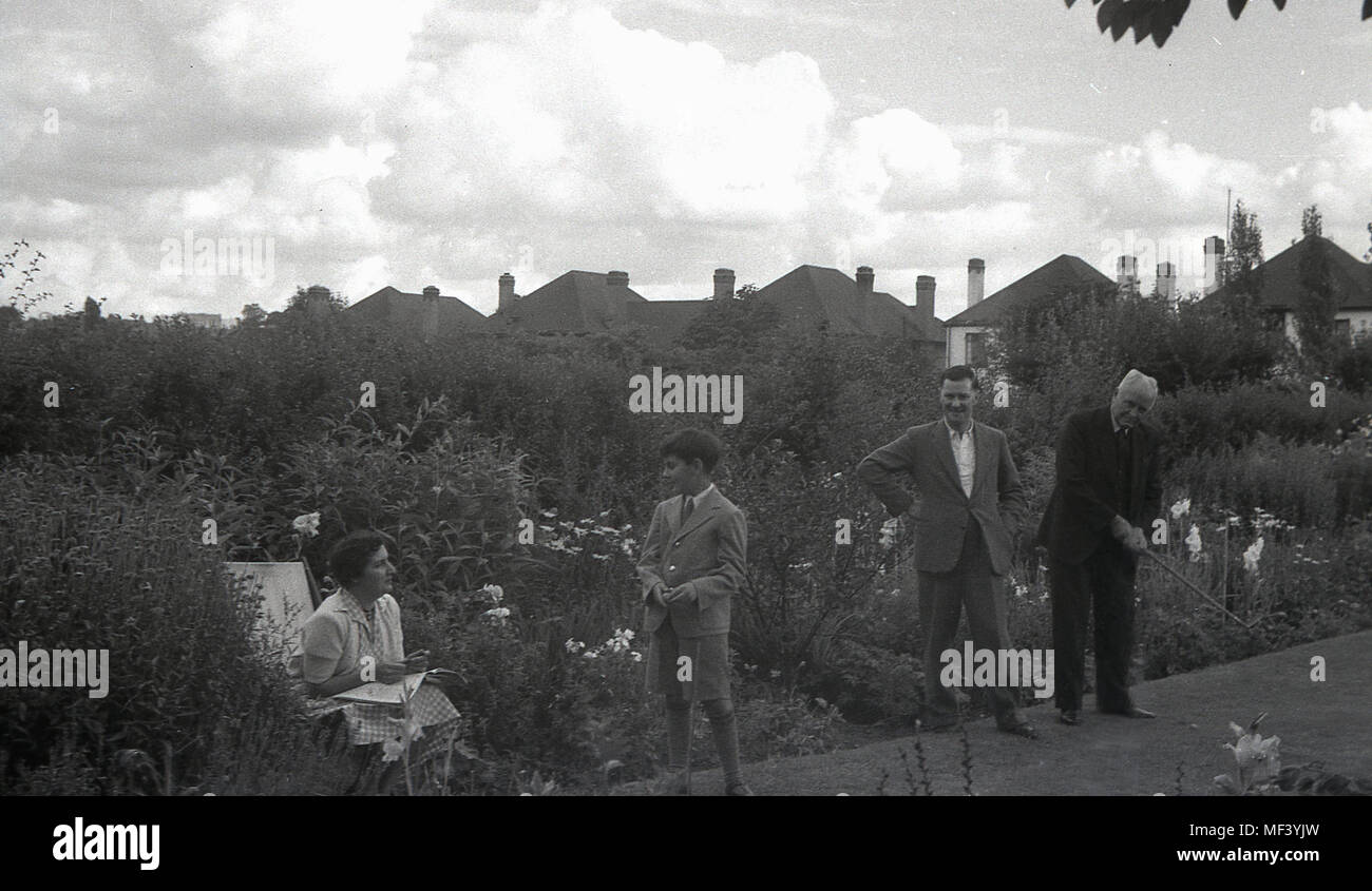 1950, storico, Londra, padre e figlio e nonno insieme sul prato del backgarden, avente una messa la concorrenza. Foto Stock