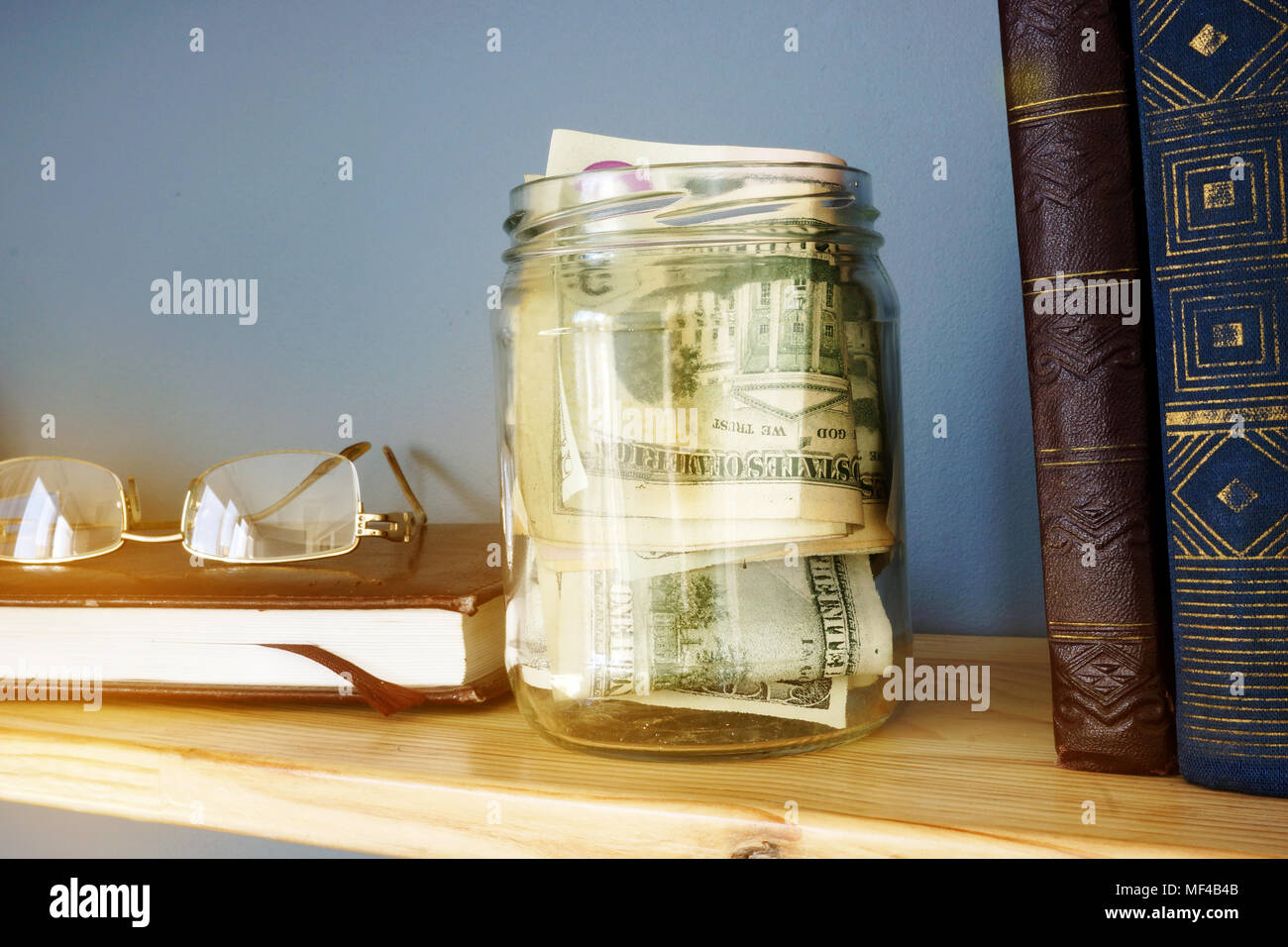 Vaso con denaro su un ripiano. Risparmi e finanze home. Foto Stock