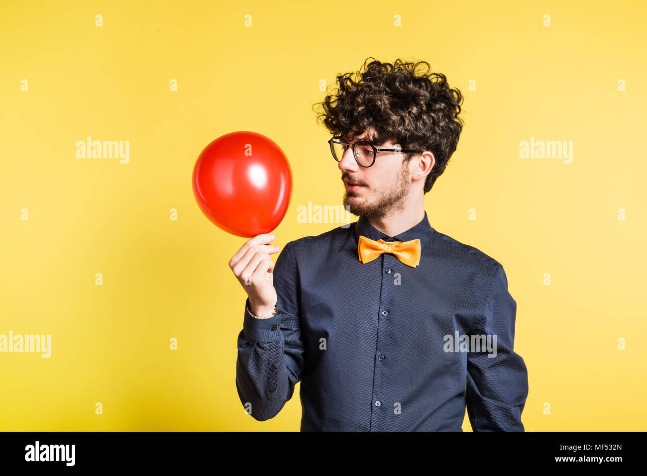 Ritratto di un giovane uomo con palloncino in uno studio su uno sfondo giallo. Foto Stock