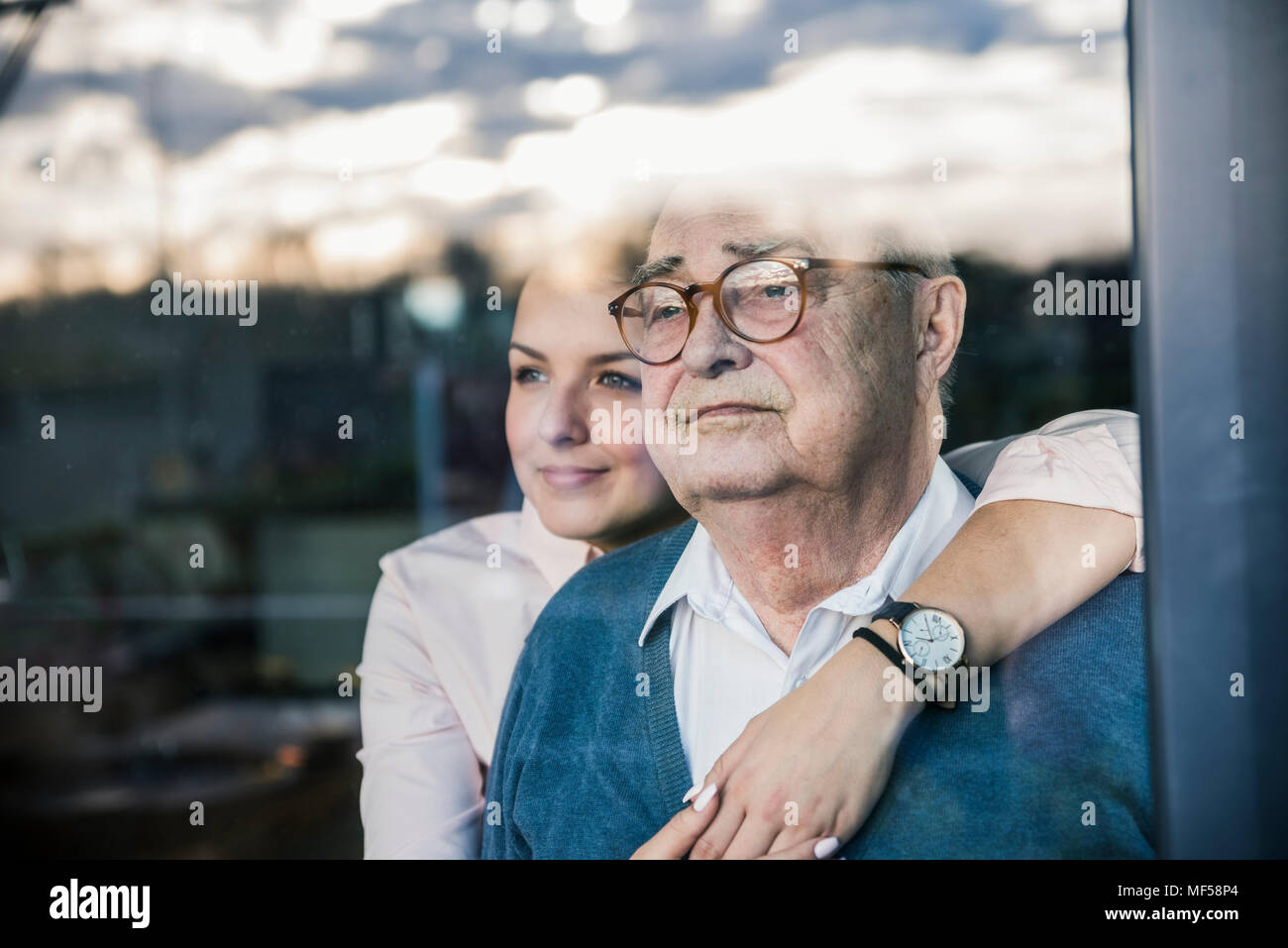 Ritratto di giovane donna abbracciando il senior man a finestra Foto Stock