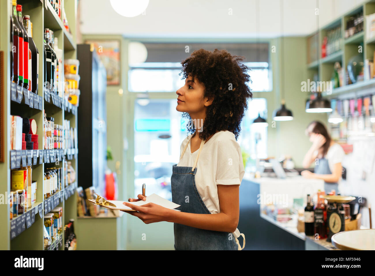 Donna con appunti a scaffale di un negozio Foto Stock