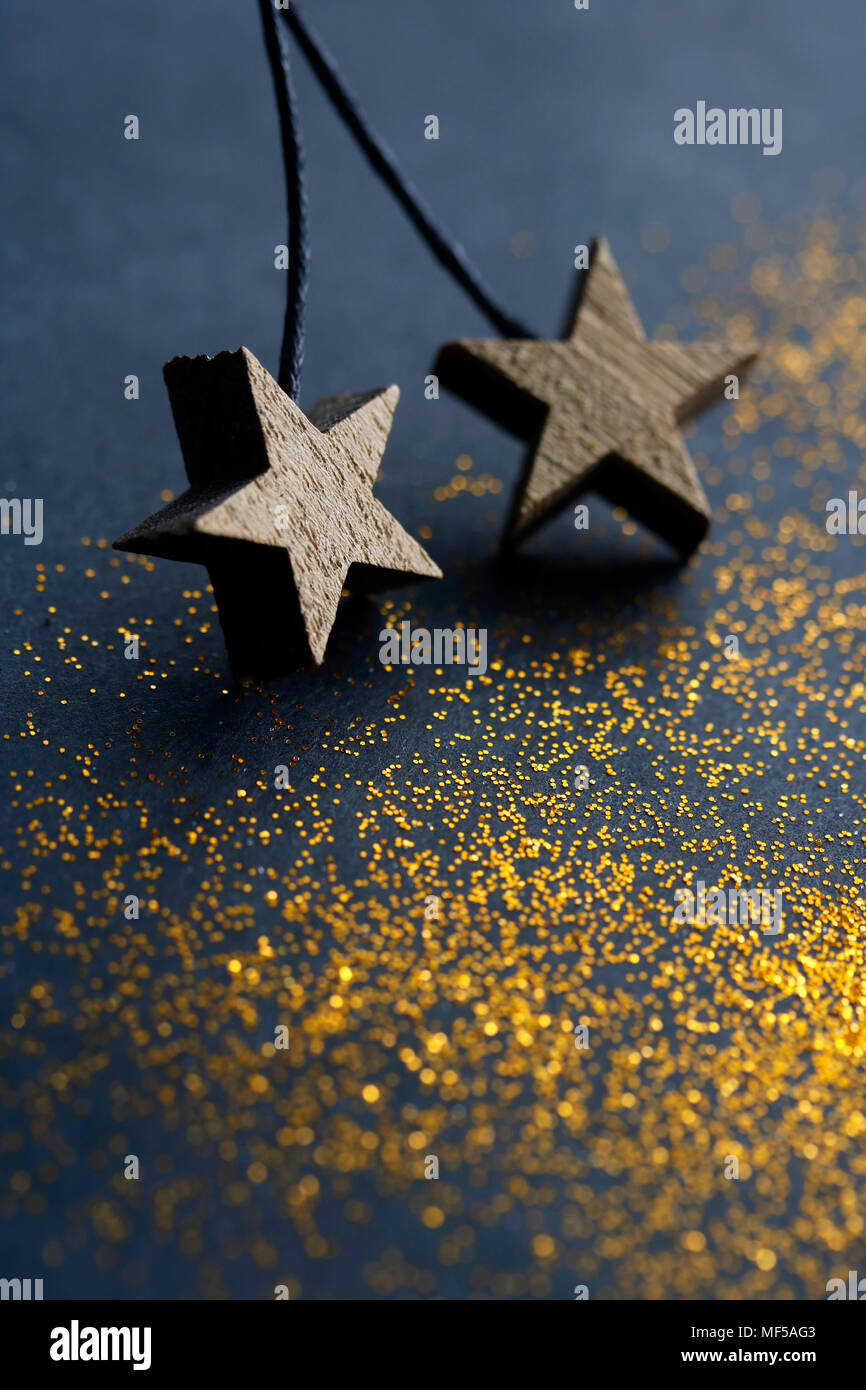Stelle di legno su sfondo scuro con golden glitter Foto Stock