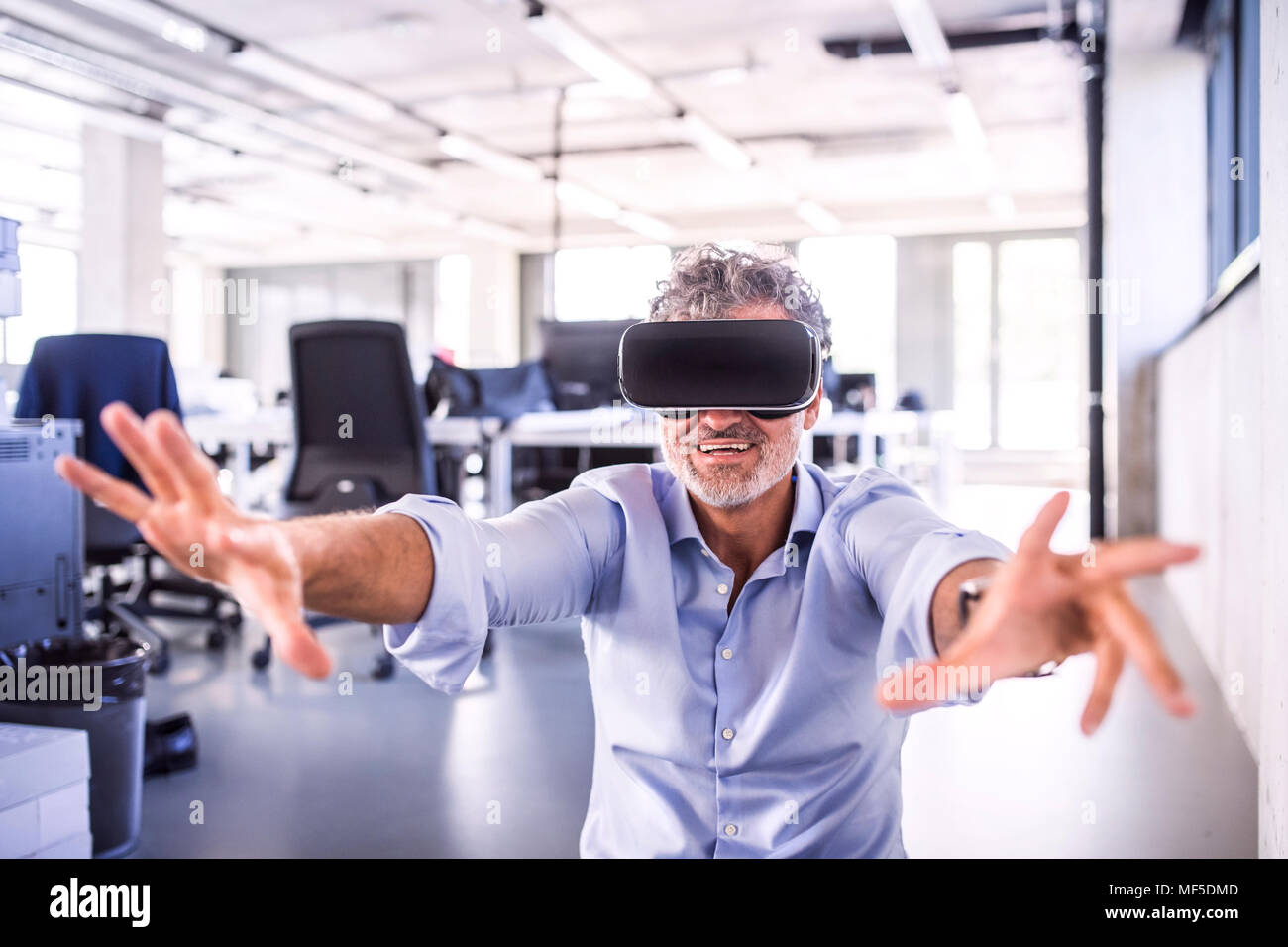 Happy businessman maturo indossando occhiali VR in office Foto Stock