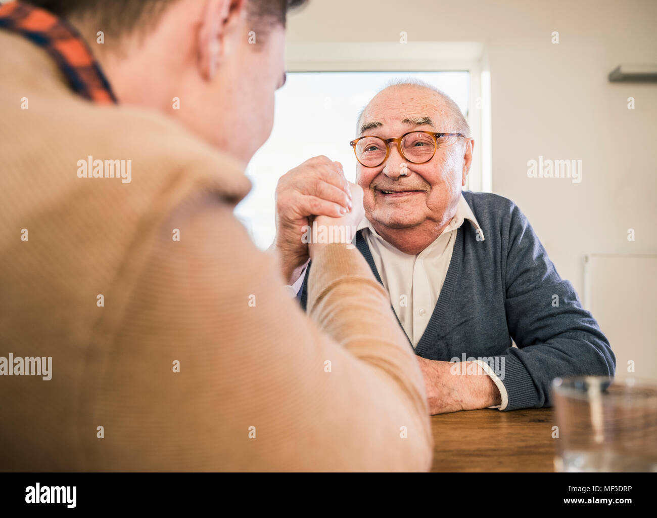 Sorridente uomo senior braccio di wrestling con giovane uomo Foto Stock