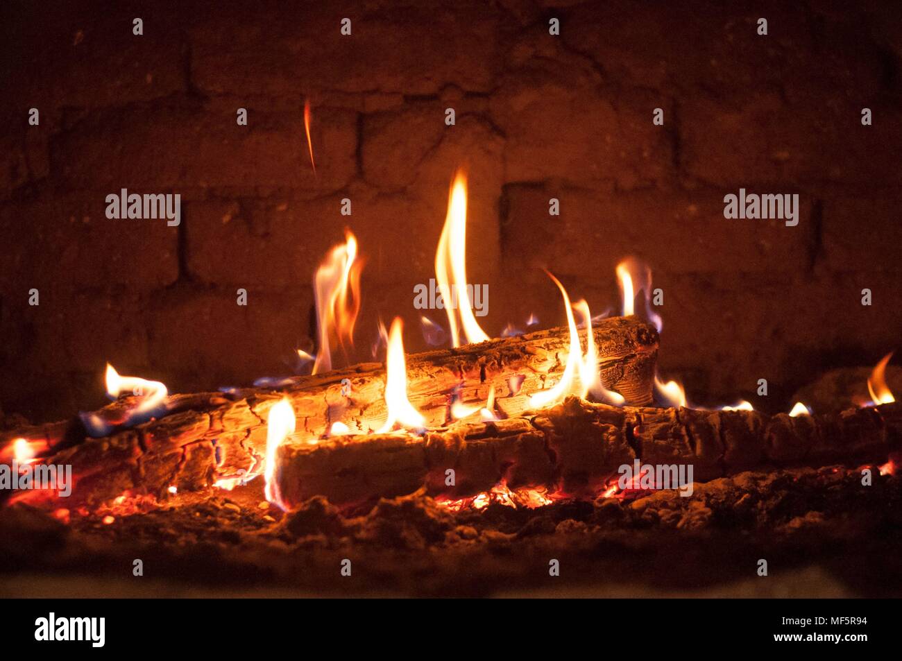 Piccolo incendio nel forno contro un muro di mattoni in background Foto Stock