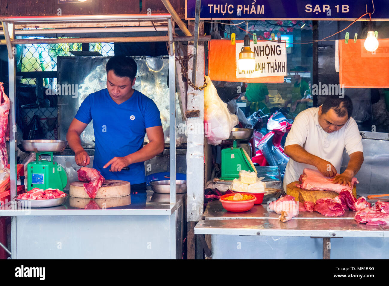 Due maschi macellai di preparare la carne nel loro macellaio le bancarelle del mercato in Ton diga che i mercati di strada, Ho Chi Minh City, Vietnam. Foto Stock