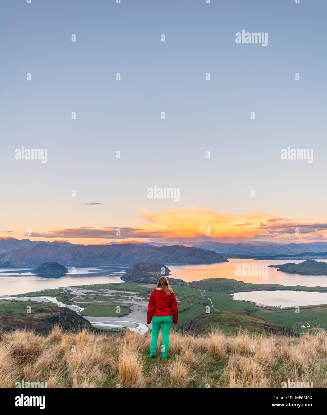 Escursionista affacciato sul lago Wanaka e montagne, tramonto, picco roccioso, Glendhu Bay, Otago Southland, Nuova Zelanda Foto Stock