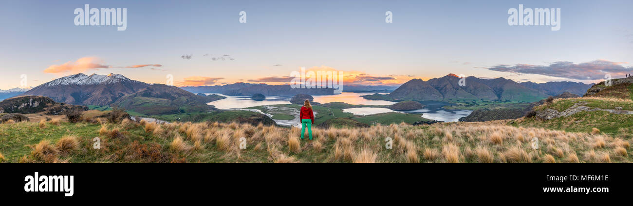 Escursionista affacciato sul lago Wanaka e montagne, picco roccioso, Glendhu Bay, Otago Southland, Nuova Zelanda Foto Stock