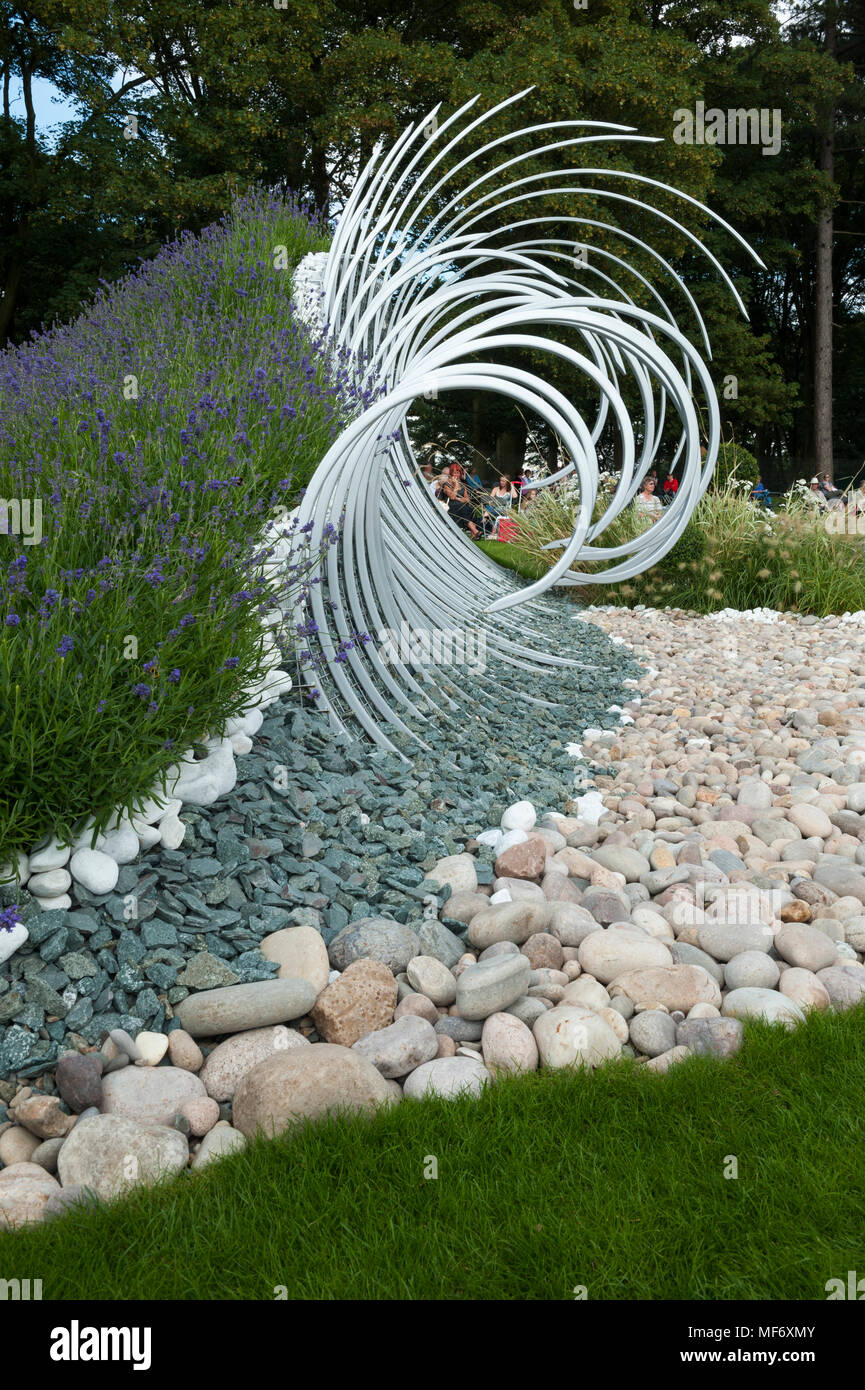 Drammatica scultura di metallo, ciottoli bianchi & pietre rappresentano le onde che si infrangono sulla battigia in 'Wave Dance' garden - RHS Flower Show, Tatton Park, England, Regno Unito Foto Stock