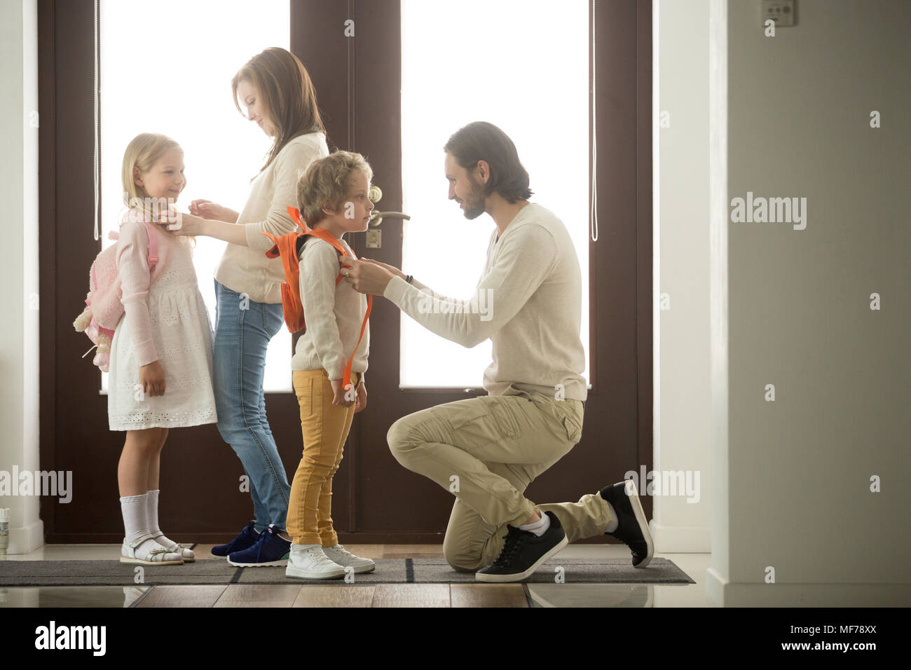 I genitori aiutano i bambini la preparazione di andare a scuola a piedi presso il padiglione Foto Stock