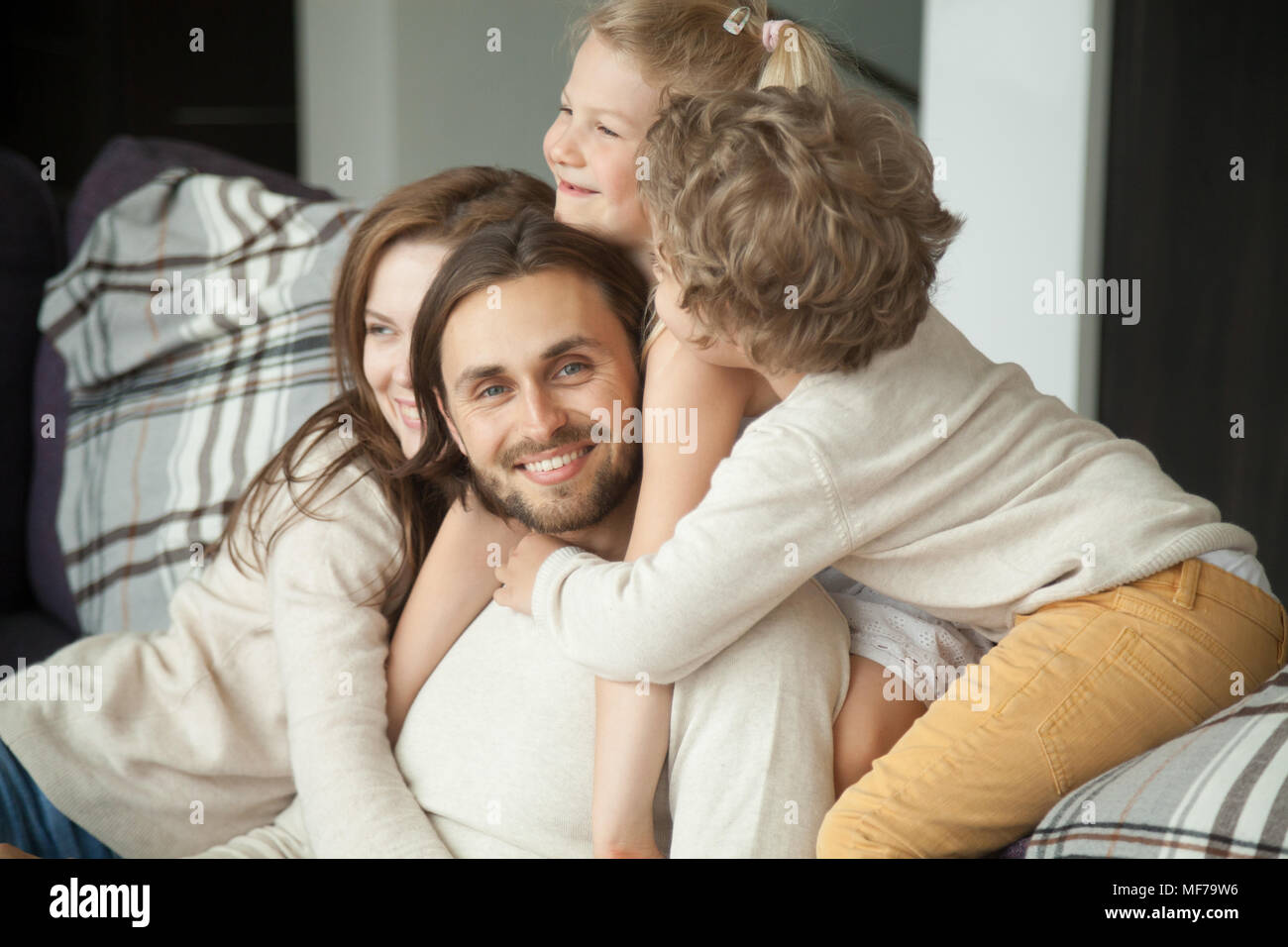 Papà sorridente guardando la telecamera godendo kids moglie abbracciando fathe Foto Stock