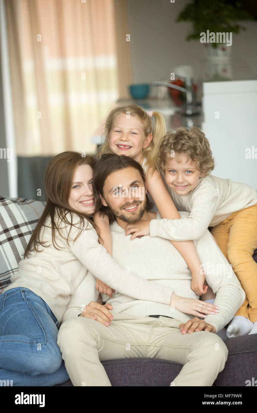 La famiglia felice con bambini sul divano guardando la telecamera, ritratto Foto Stock