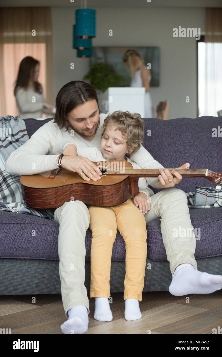 Papà attento insegnamento kid figlio a suonare la chitarra a casa Foto Stock