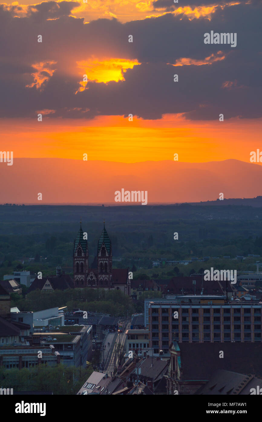 Germania, città Freiburg im Breisgau vista aerea su Chiesa e città del treno con la masterizzazione arancione tramonto Cielo Foto Stock