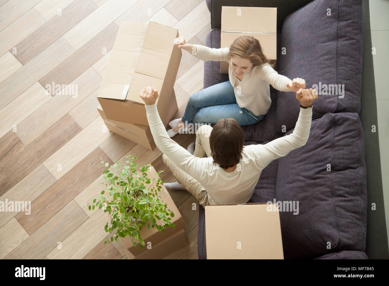 Giovane alzando le mani celebrando in movimento nella nuova casa, vista dall'alto Foto Stock