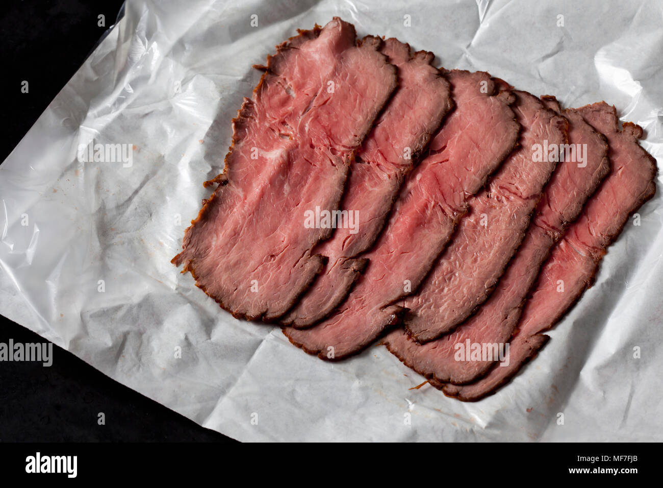 Sei fette di arrosto di manzo sulla carta oleata Foto Stock