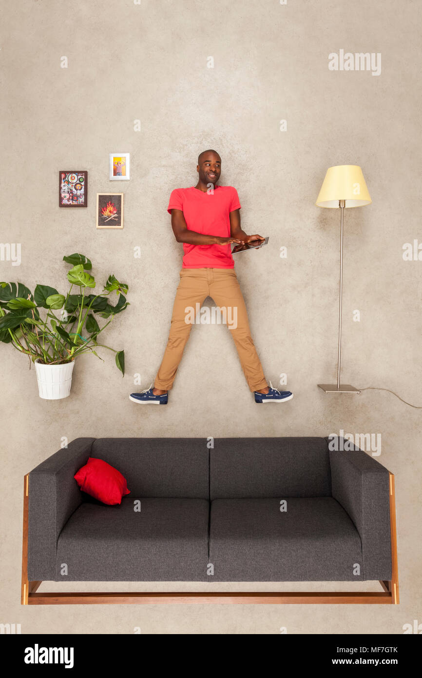 Uomo a casa nel suo soggiorno utilizzando tablet Foto Stock