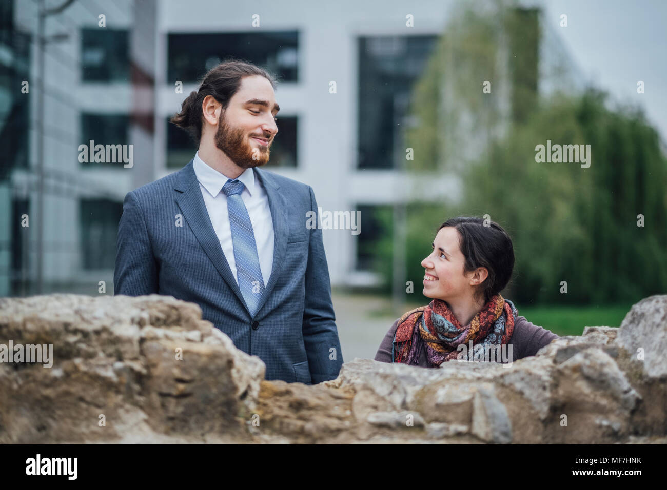 Imprenditore sorridente e la donna dietro un muro esterno edificio per uffici Foto Stock