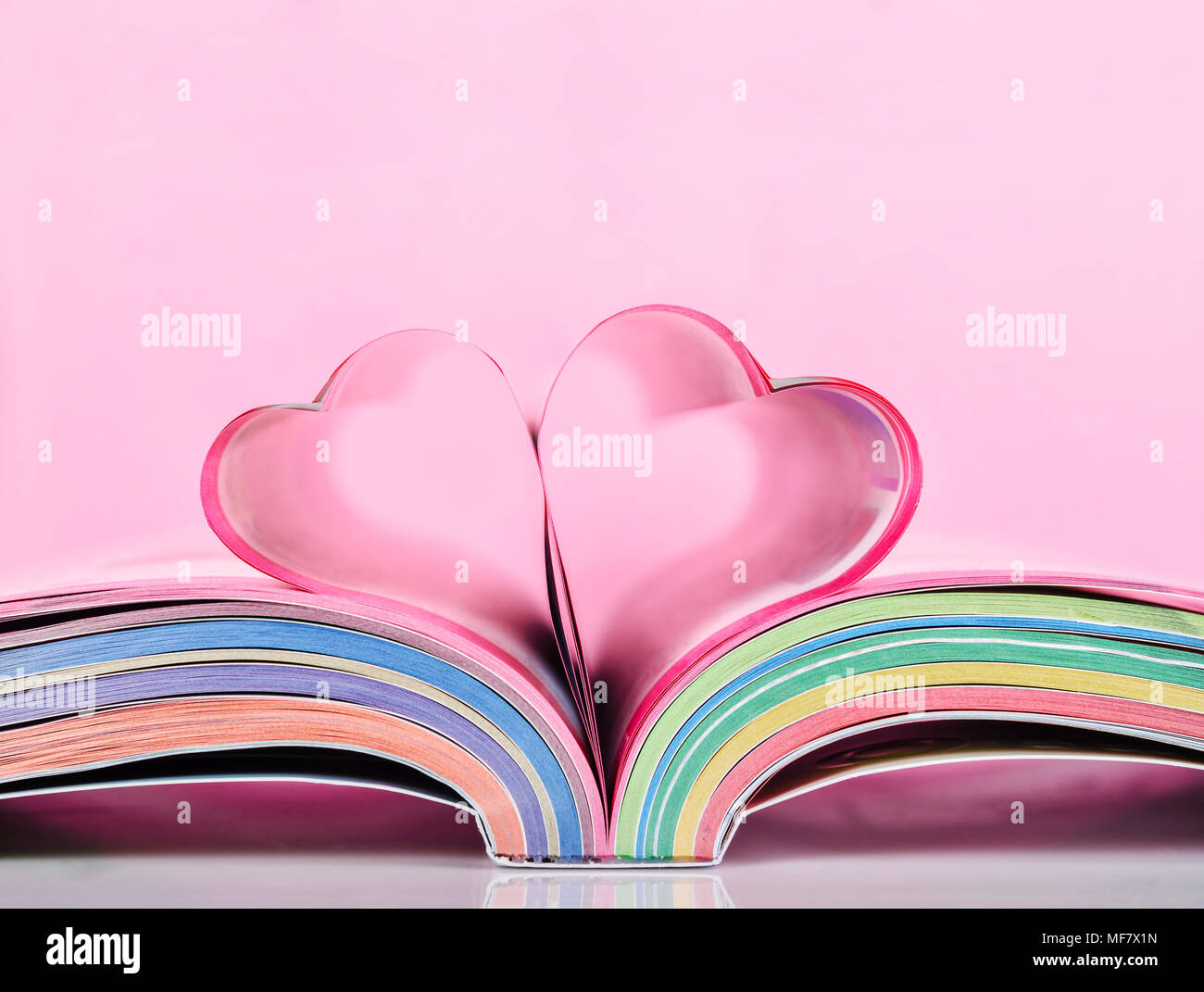 Prenota con pagine aperte e la forma di cuore su sfondo rosa. Foto Stock