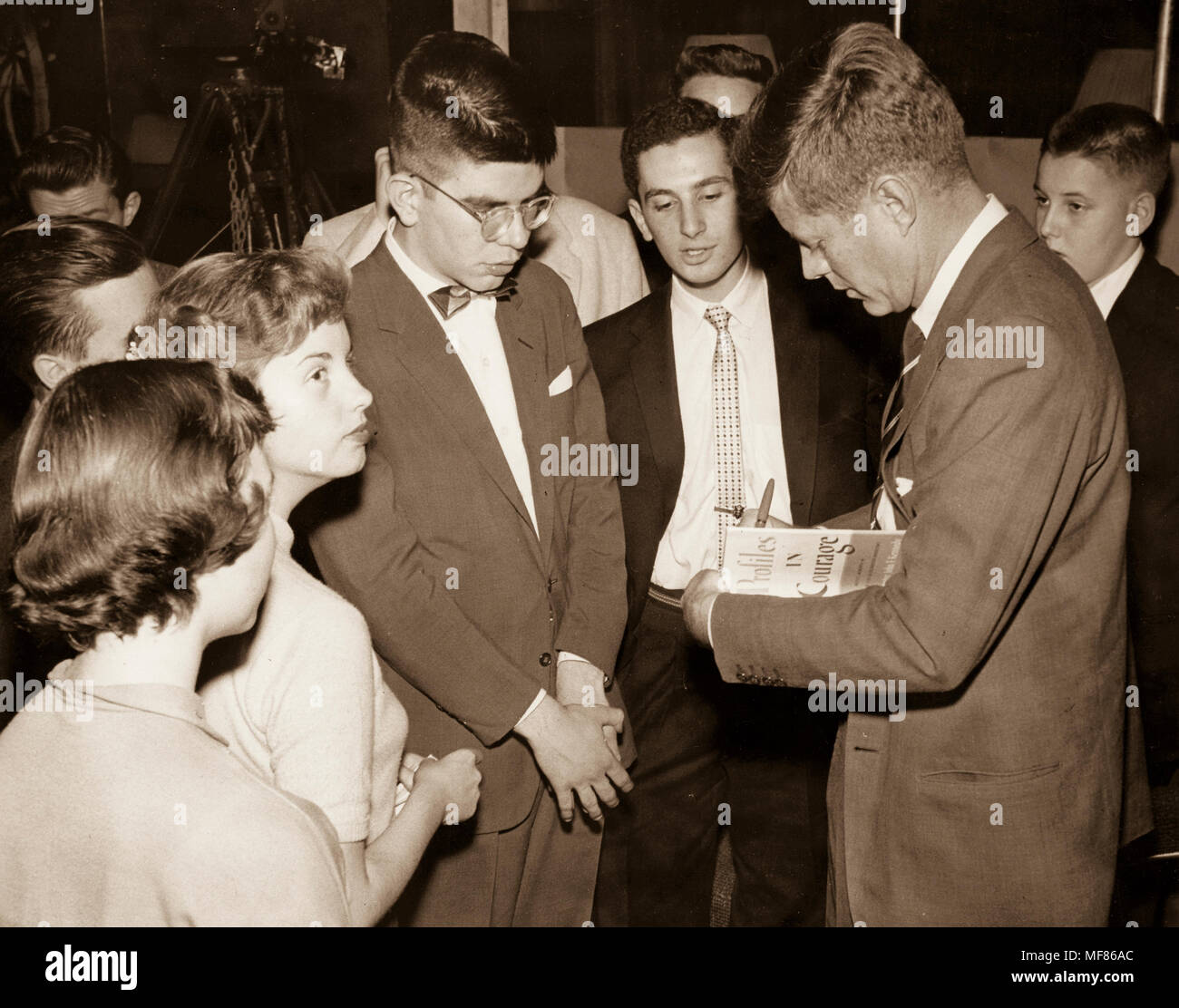 PC780 c.1956-1957 Senatore John Fitzgerald Kennedy segni una copia di 'Profili in coraggio" per un giovane fan. Fotografo sconosciuto in John F. Kennedy Presidential Library and Museum di Boston. Foto Stock