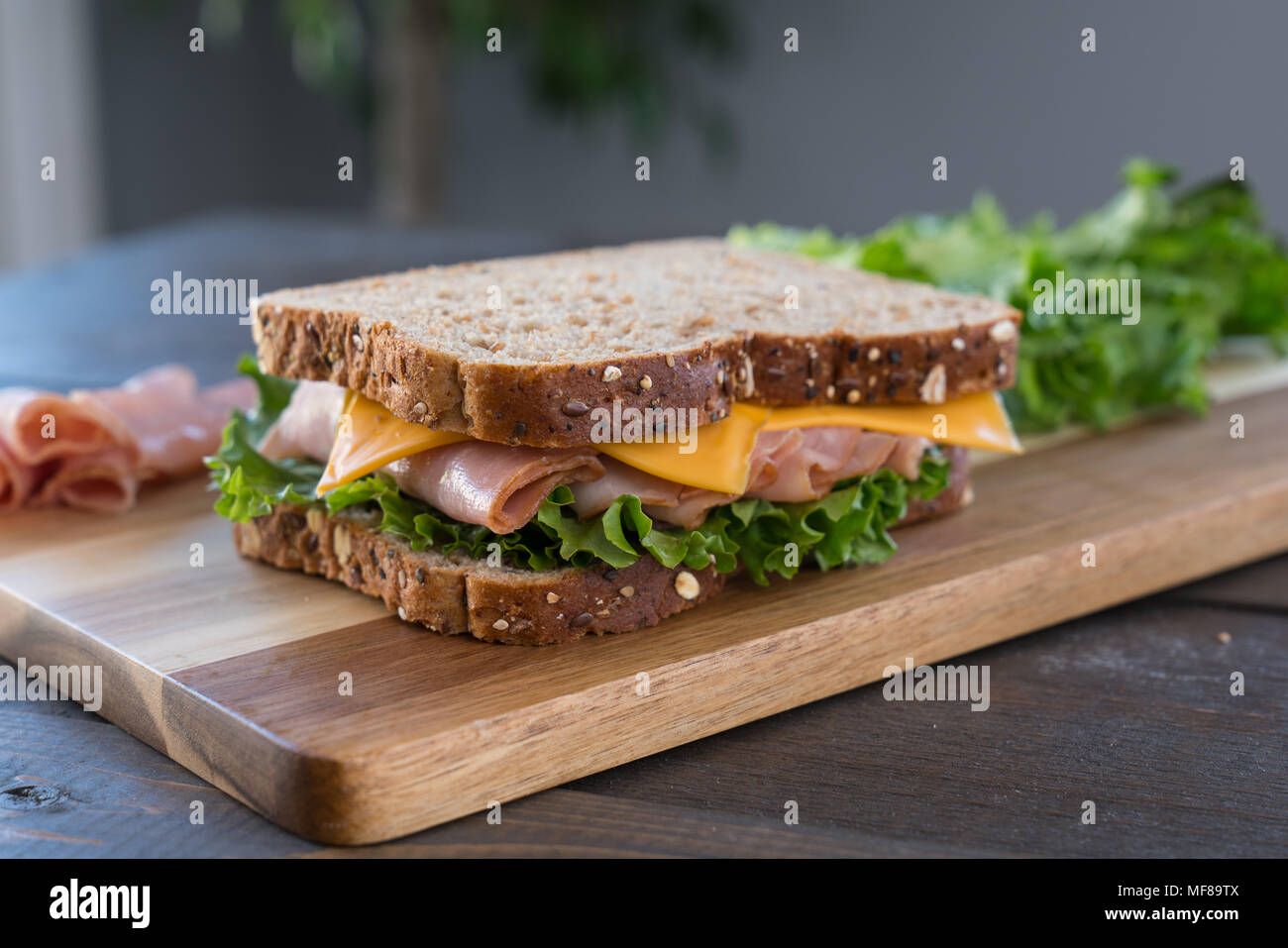 Fresco prosciutto e formaggio in sandwich di pane integrale sul bordo di taglio Foto Stock