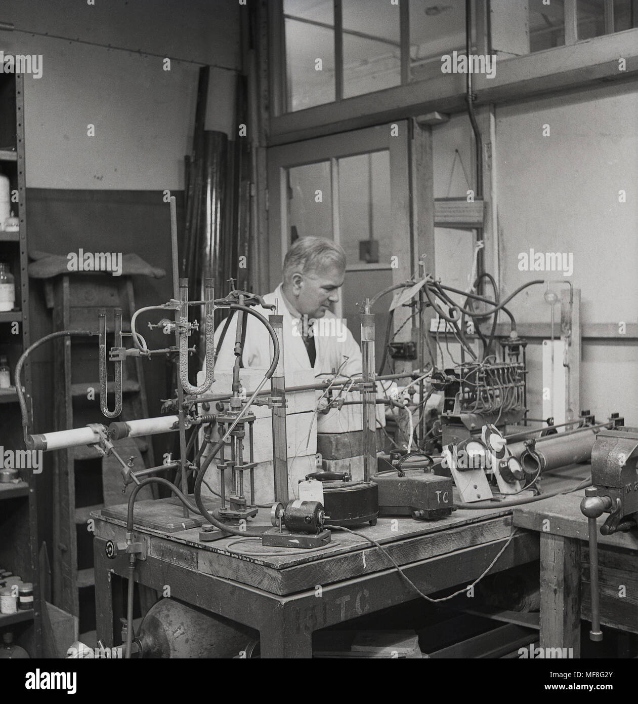 1948, storico, maschio scienza chimico presso un banco in laboratorio utilizzando l'apparecchiatura del giorno per la sua opera di ricerca di catrame di carbone - un sottoprodotto della combustione di carbone senza aria - all Università di Leeds, Dept di carbone, gas e industrie di combustibile. Molti composti commerciali sono derivati da catrame di carbone che appartiene alla classificazione, keratoplastics. Foto Stock