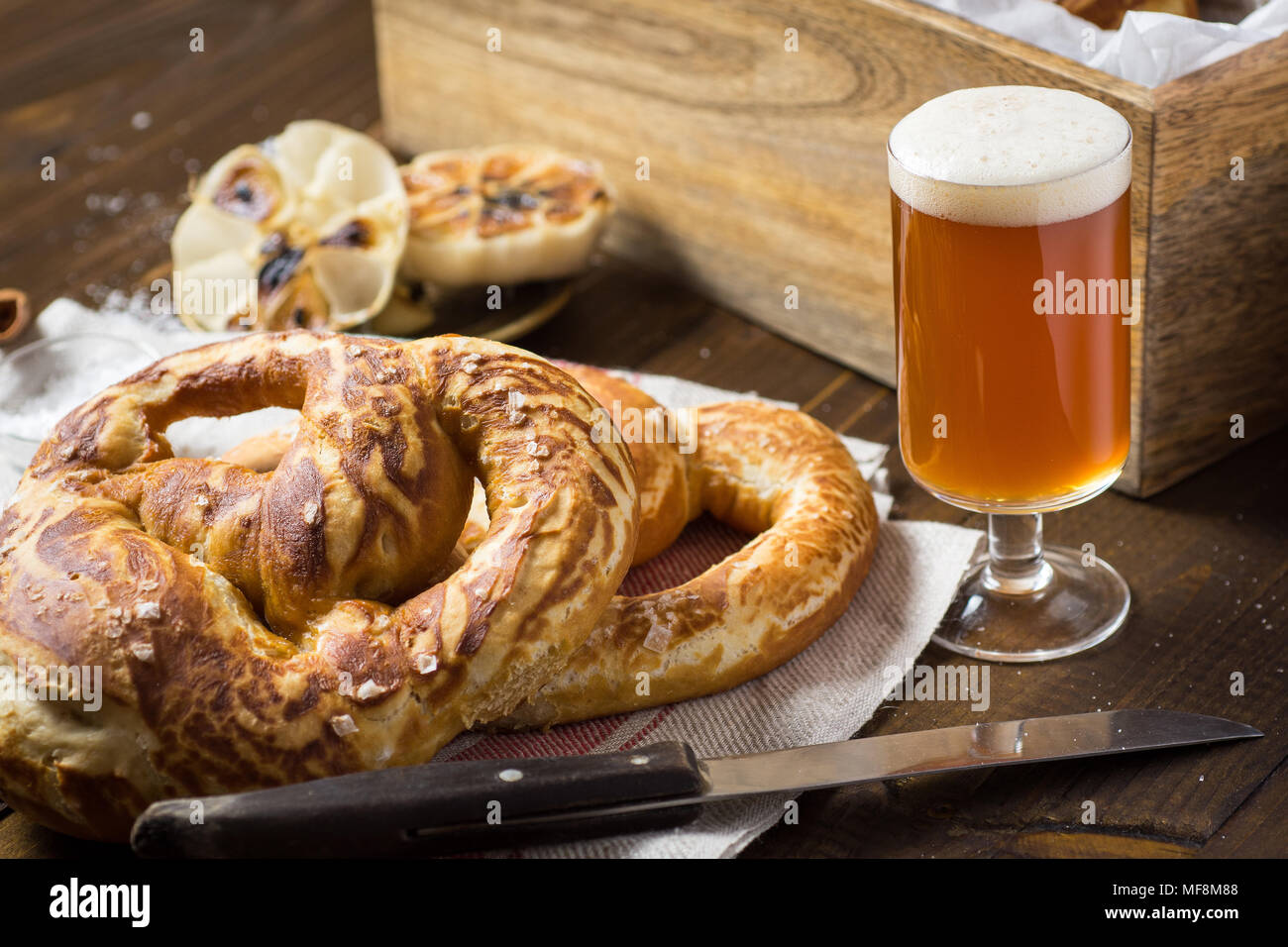 In casa Pretzel con sale marino e bicchiere di birra su tavola in legno rustico Foto Stock