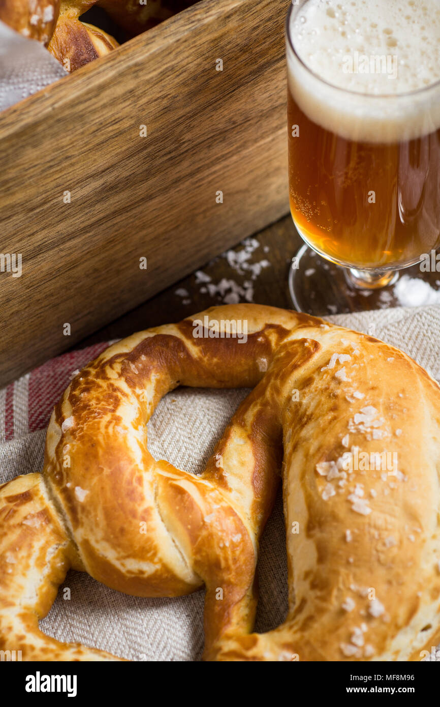 In casa Pretzel con sale marino e bicchiere di birra su tavola in legno rustico Foto Stock